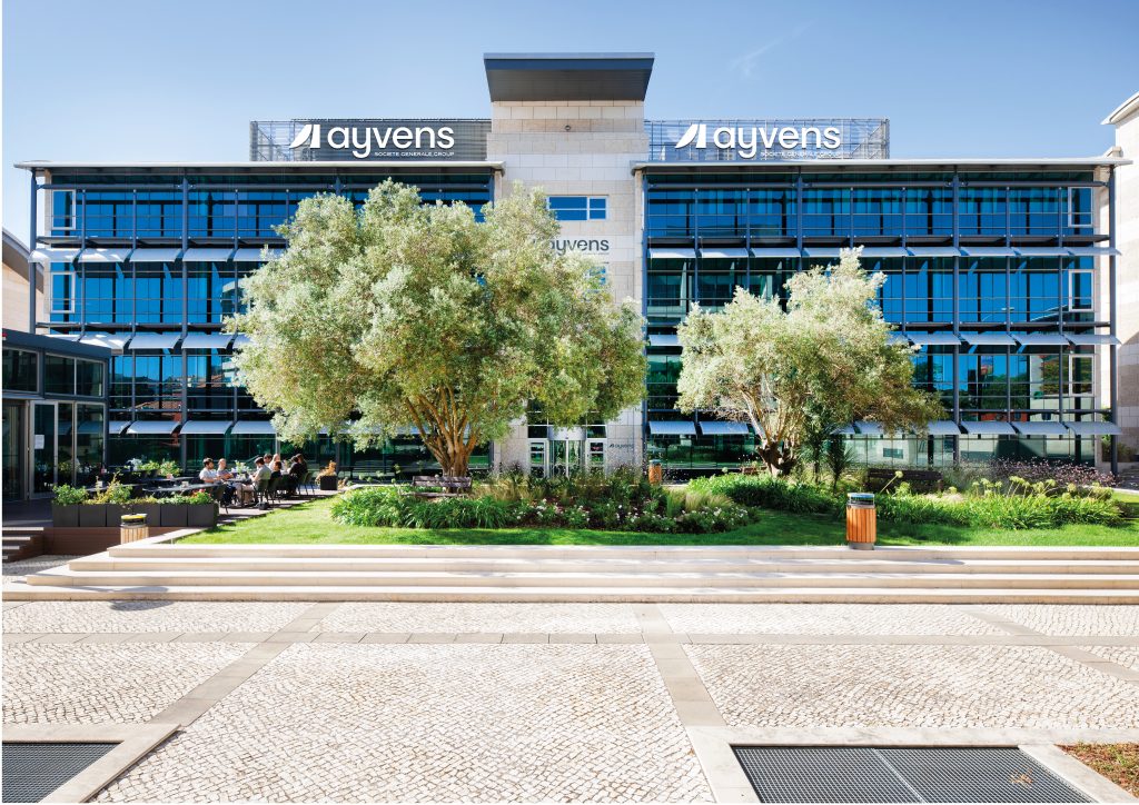 Fotomontagem apresentando o conceito de Aplicação na fachada do logótipo no projeto Ayvens, localizado em Oeiras, Portugal.