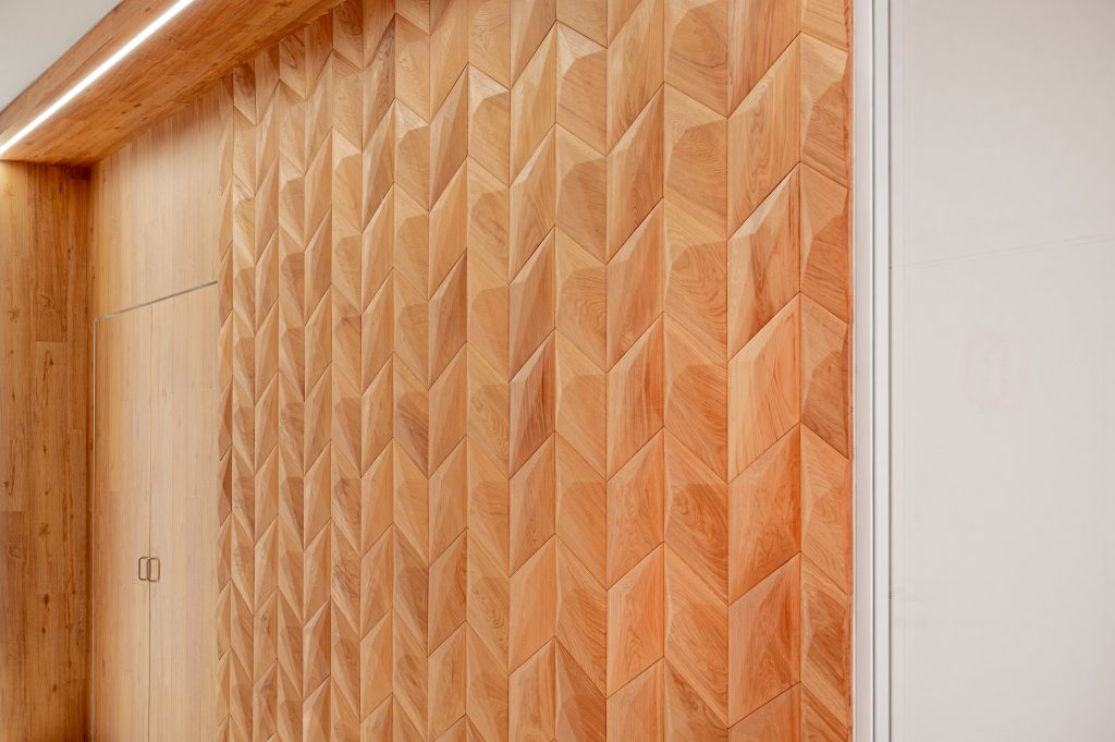 Fotografia apresentando o conceito de detalhe do painel de madeira, Recepção no projeto Sede Banco Primus, localizado em Oeiras, Portugal.