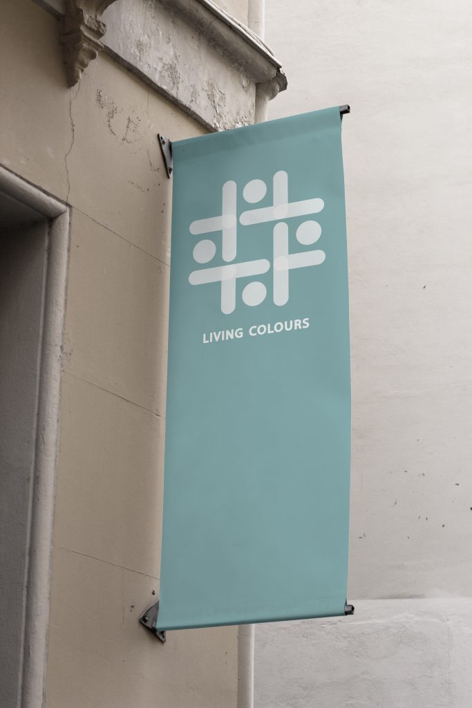 Fotomontagem apresentando a Aplicação em banner no projeto Logótipo Living Colours, localizado em Lisboa, Portugal.