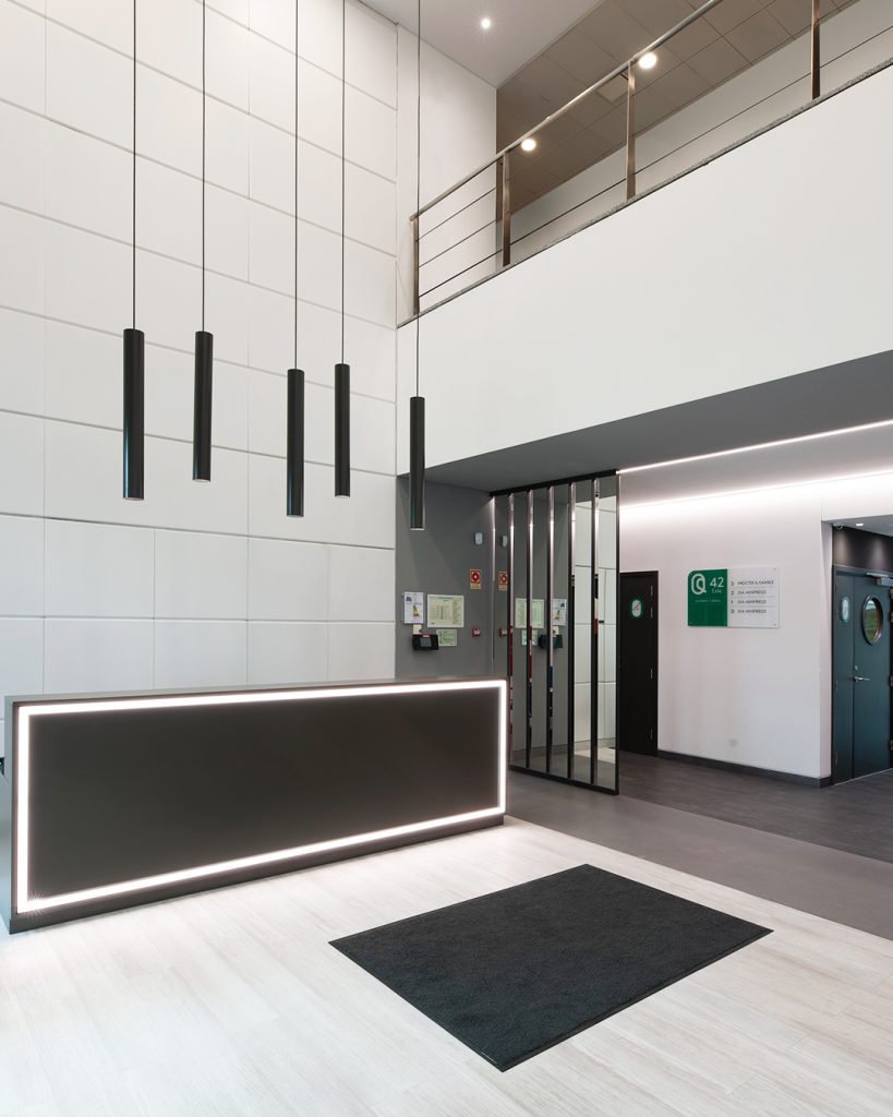 Fotografia apresentando o conceito de Vista da entrada e balcão da recepção no projeto Lobby Q42, localizado em Oeiras, Portugal.
