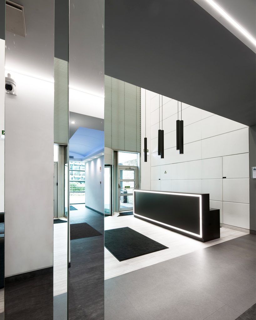 Fotografia apresentando o conceito de Vista da entrada e balcão da recepção no projeto Lobby Q42, localizado em Oeiras, Portugal.