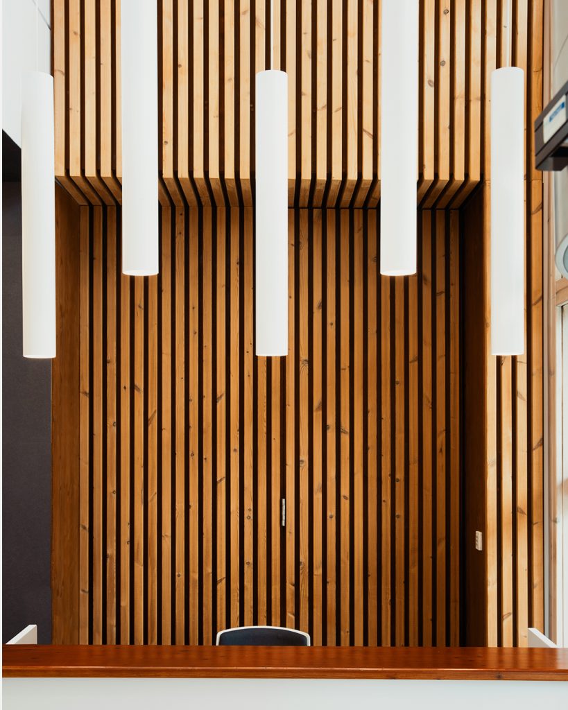 Fotografia apresentando o conceito de Detalhe de iluminação e painel ripado no projeto Lobby Q45, localizado em Oeiras, Portugal.